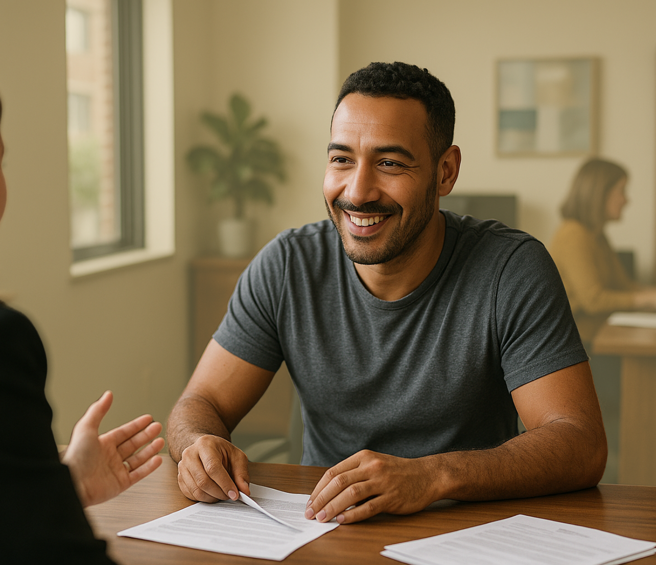 A man sits at a desk with account papers while speaking to someone across the table.
